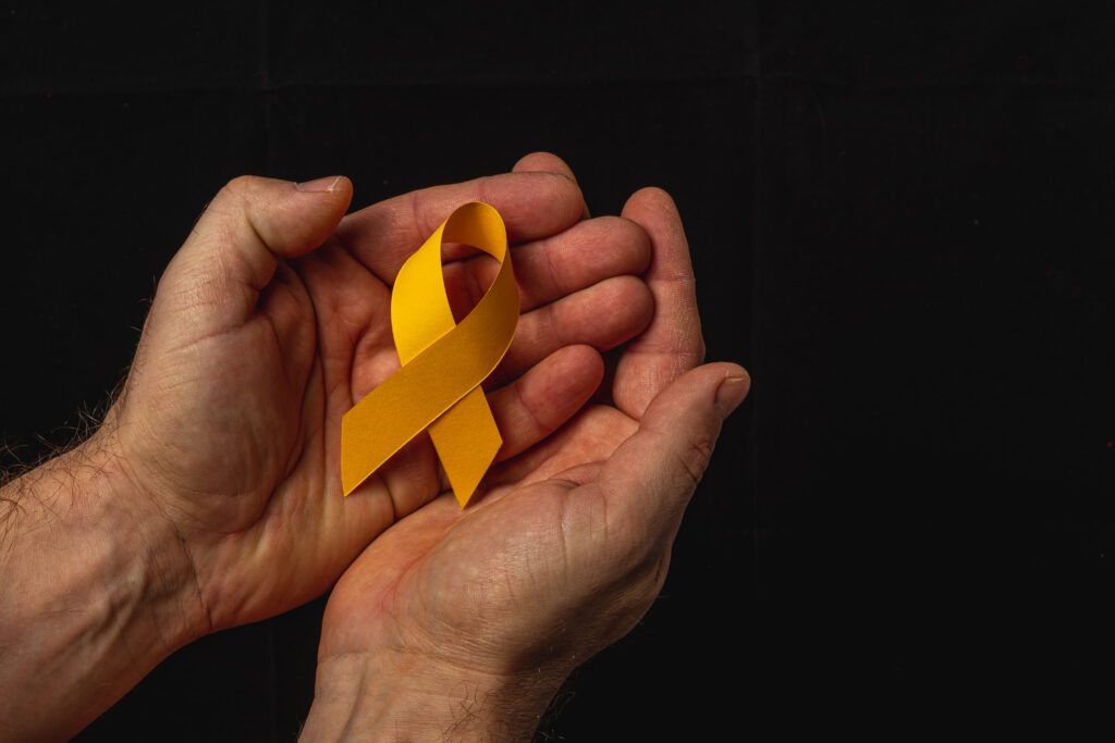 Duas mãos seguram delicadamente uma fita amarela que representa o setembro amarelo, mês dedicado à prevenção do suicídio e valorização da vida.
